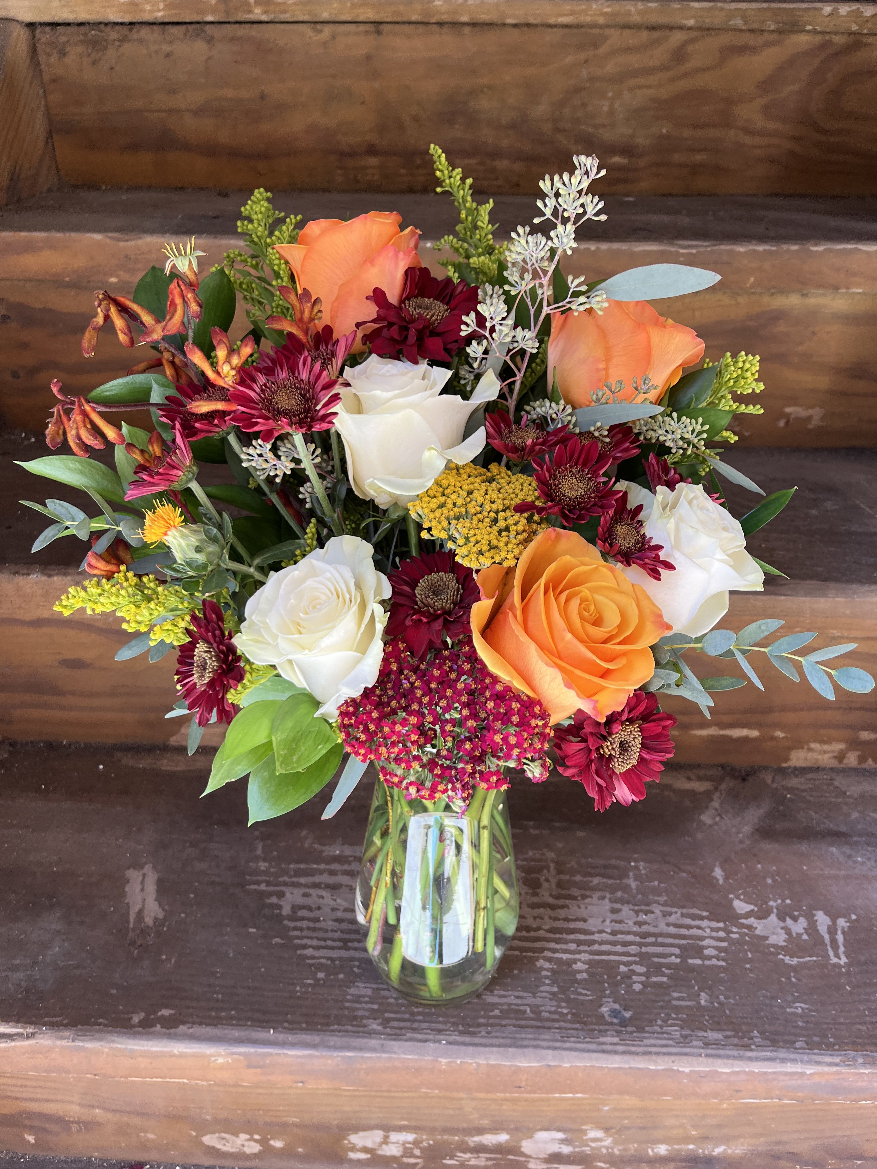 Mixed bouquet of orange and white roses in a glass vase