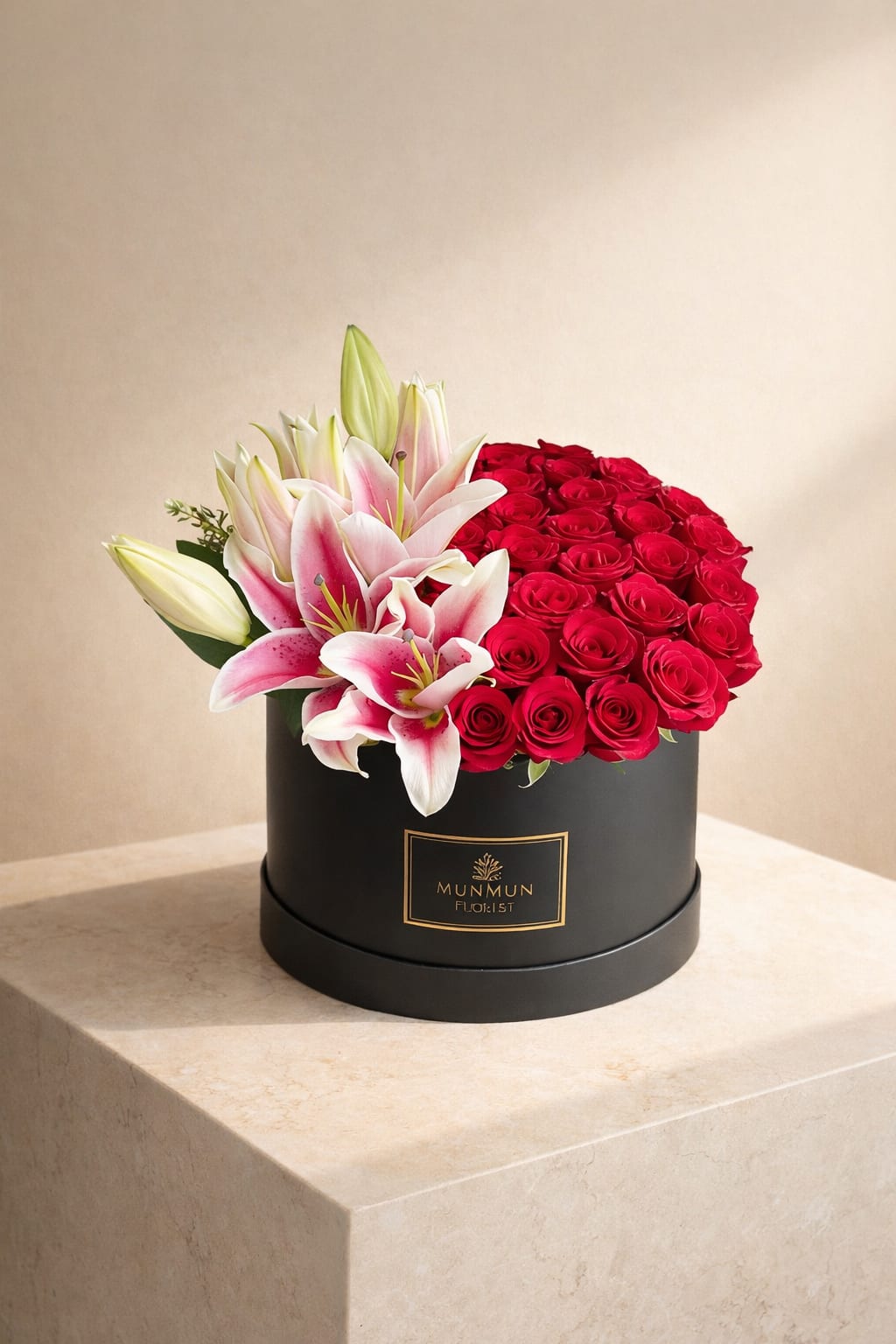 Red roses and pink lilies arranged in a black round box