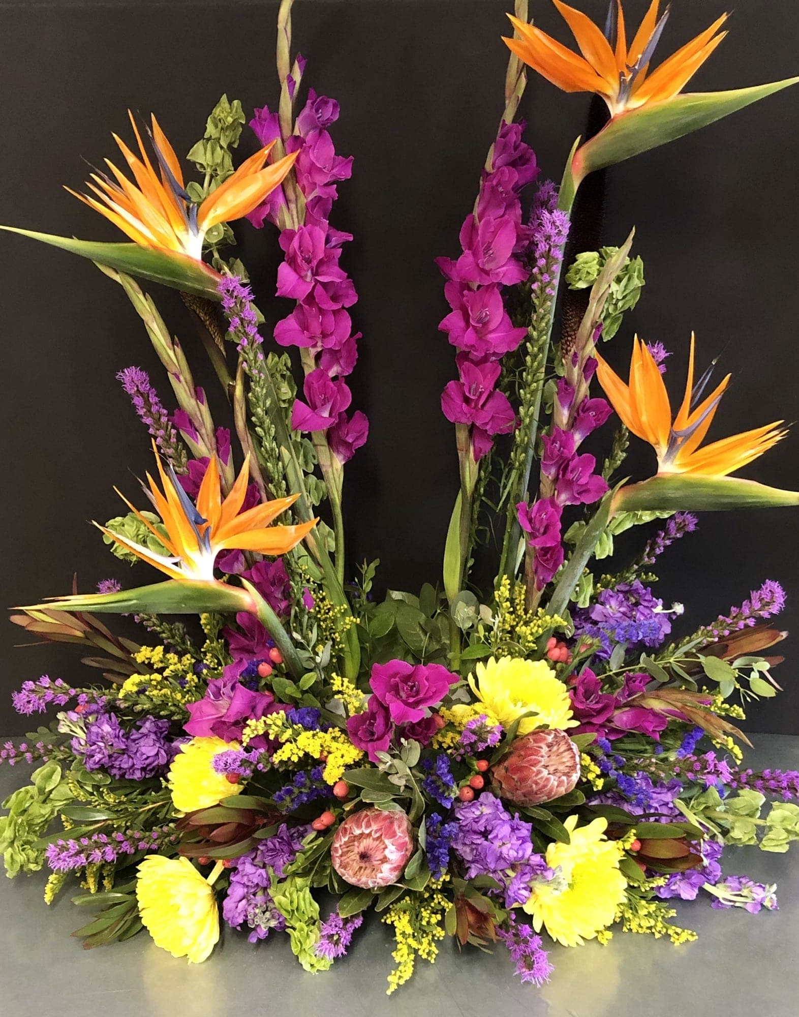 Tropical floral arrangement with orange bird-of-paradise and purple blooms