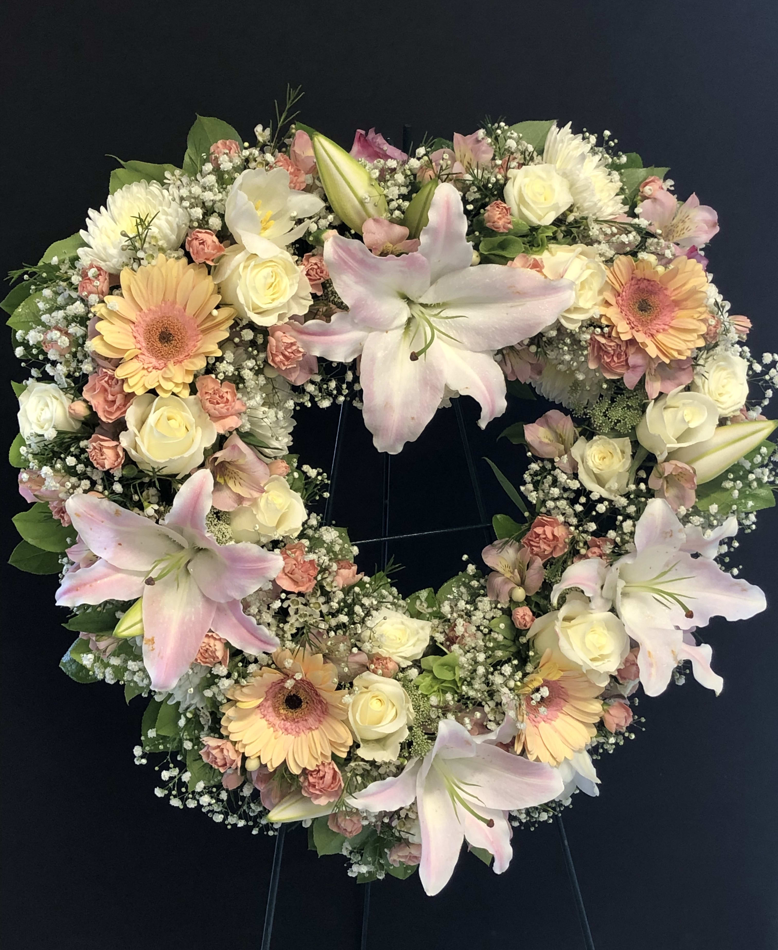 Heart-shaped floral wreath with pink lilies, cream roses, and peach gerberas