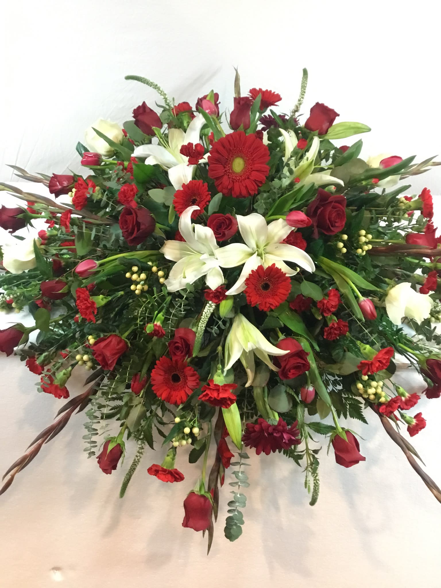 Large red, white, and green floral spray with roses and lilies