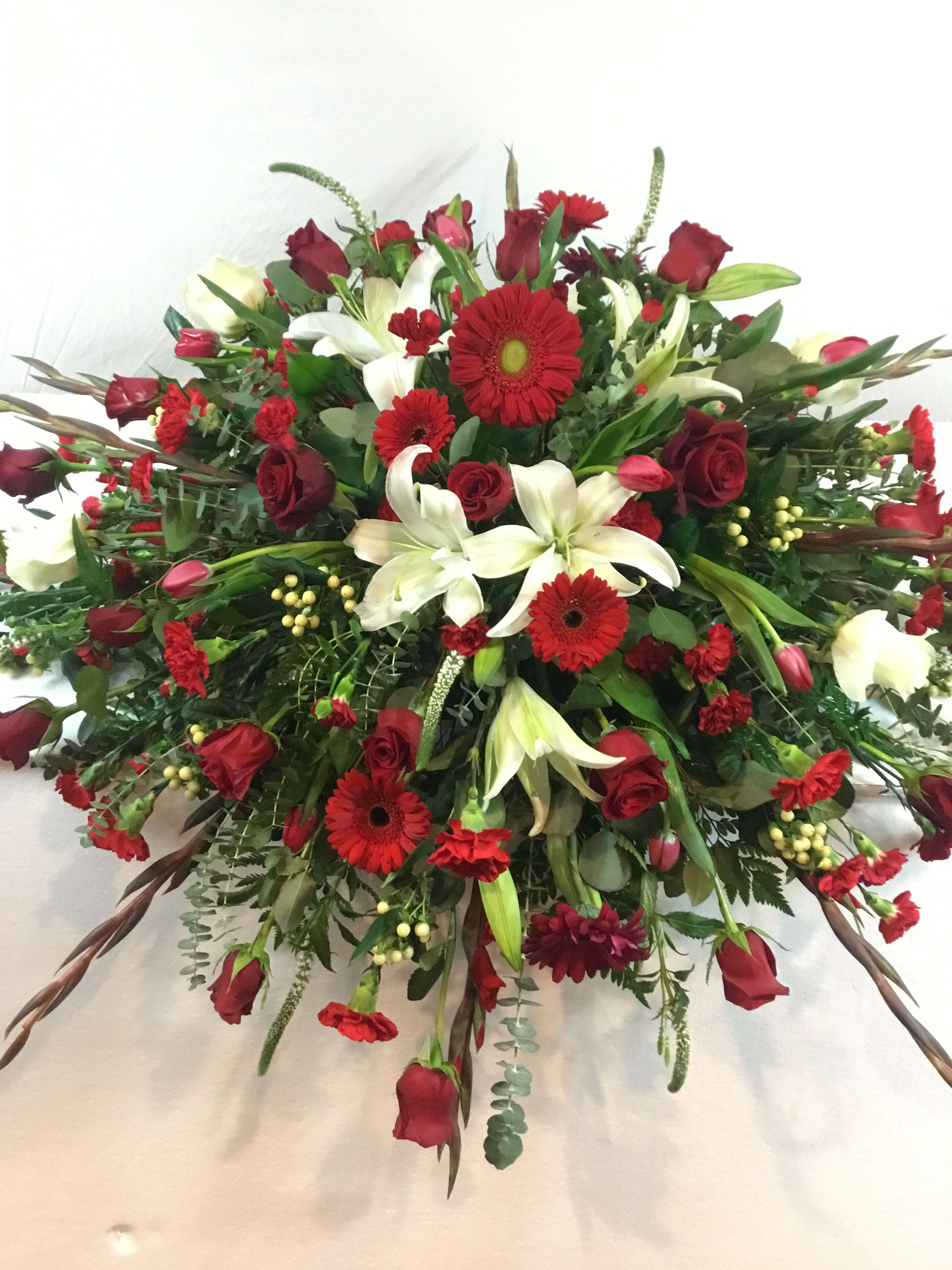 Large red and white floral spray with roses, lilies, and gerbera daisies