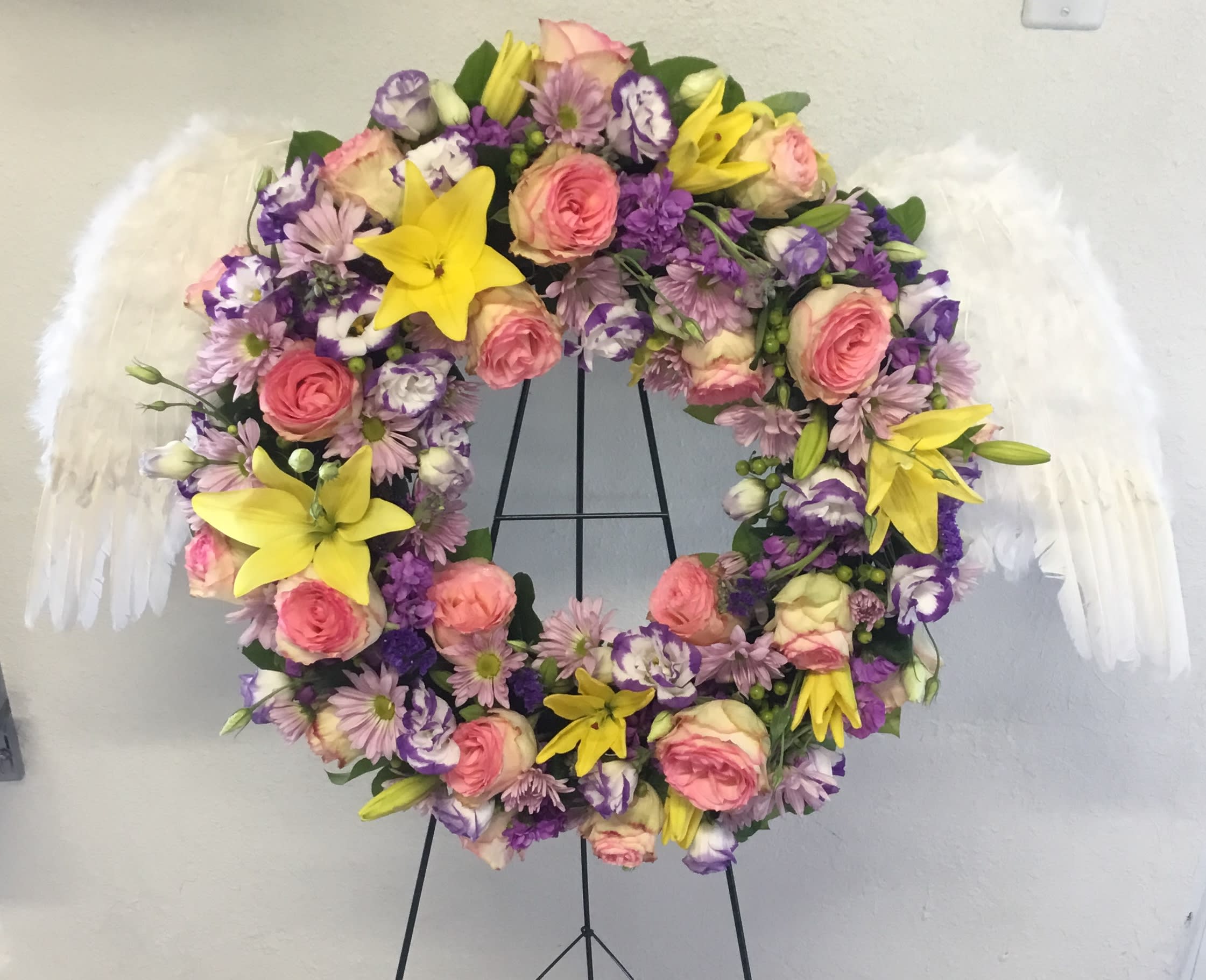 Floral wreath with pink and purple flowers and white feather wings