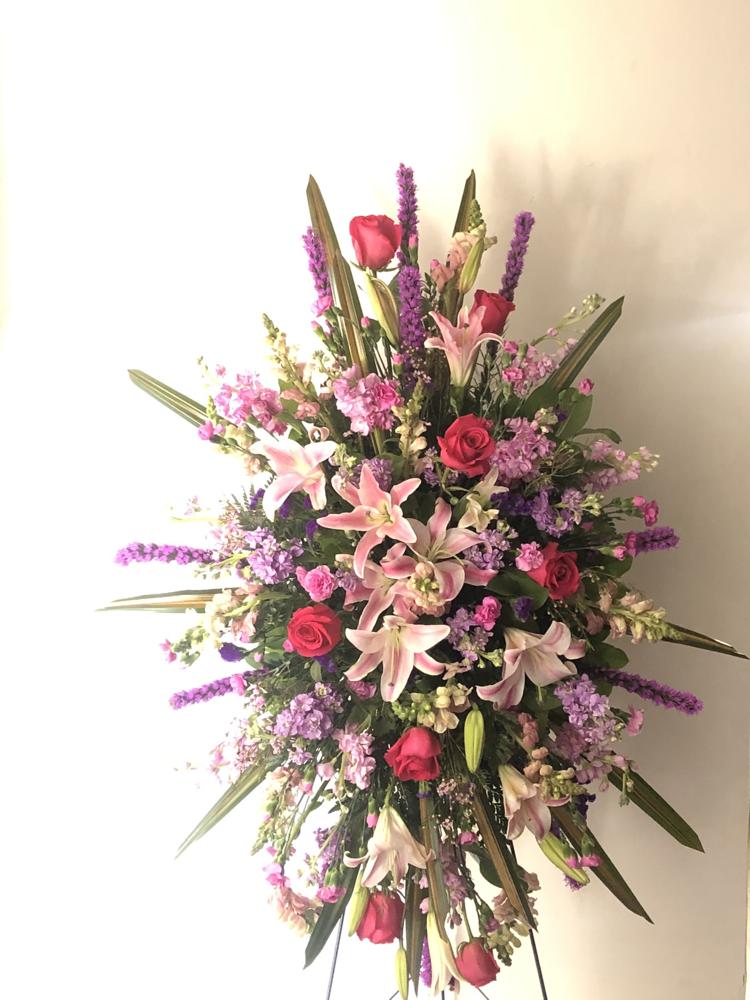 Large standing spray with pink lilies, red roses, and purple flowers