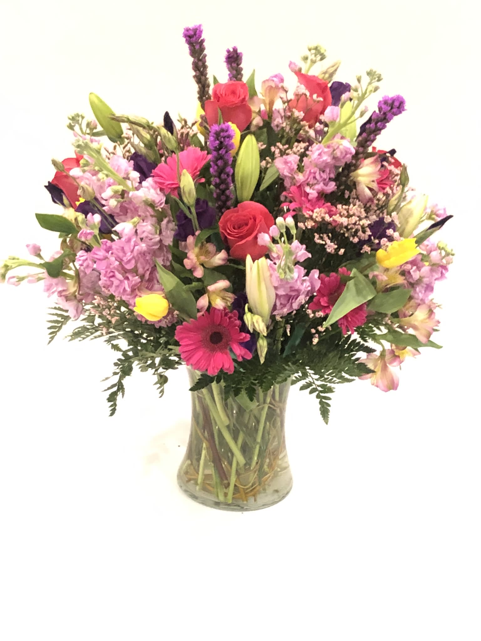 Mixed bouquet of pink, purple, and yellow flowers in a glass vase