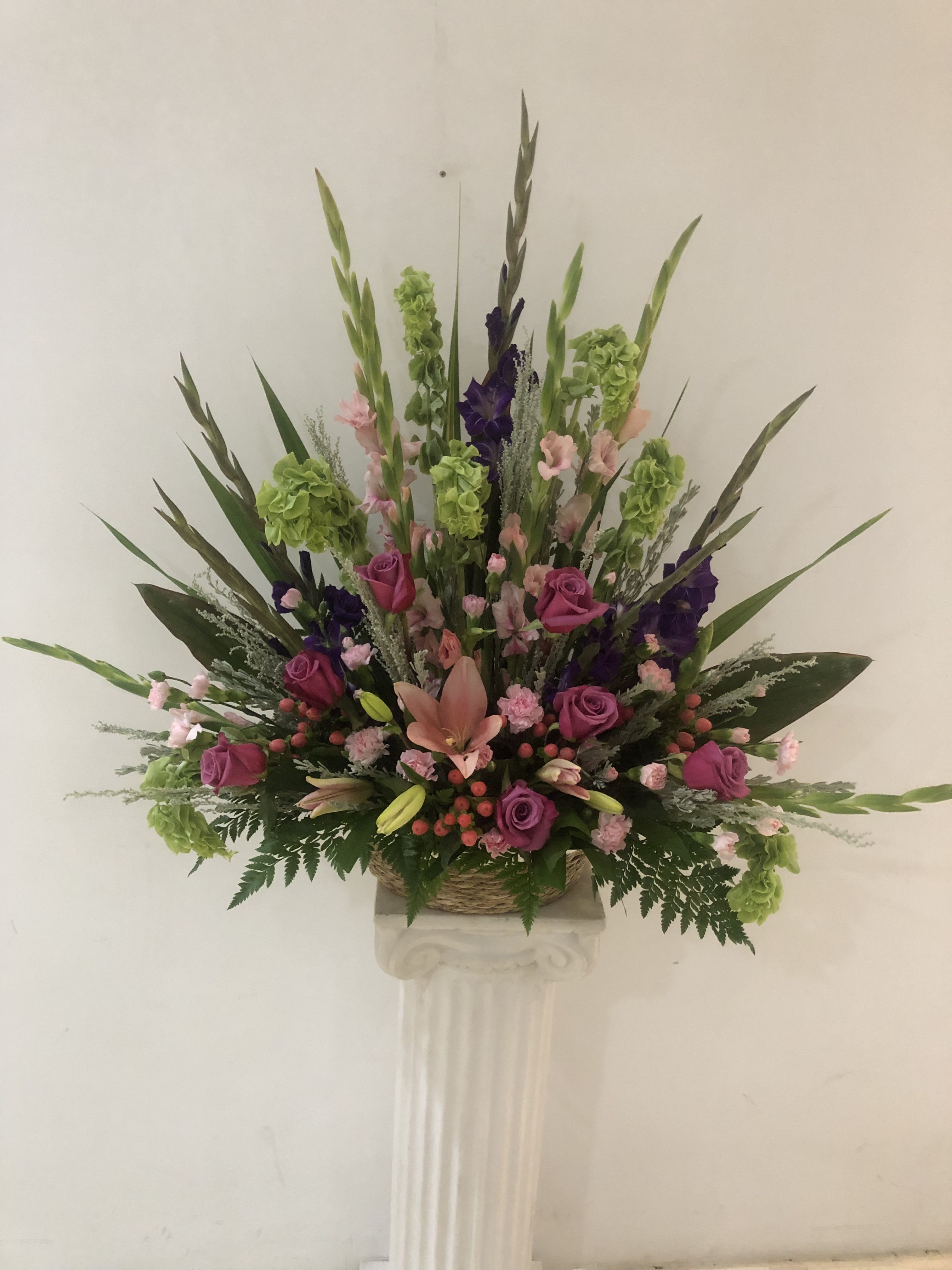 Tall floral arrangement with pink and purple roses in a basket