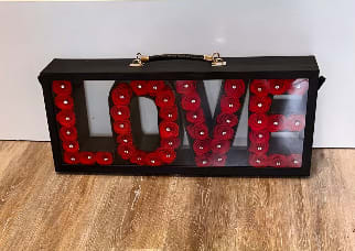 Black display case with red roses arranged to spell LOVE
