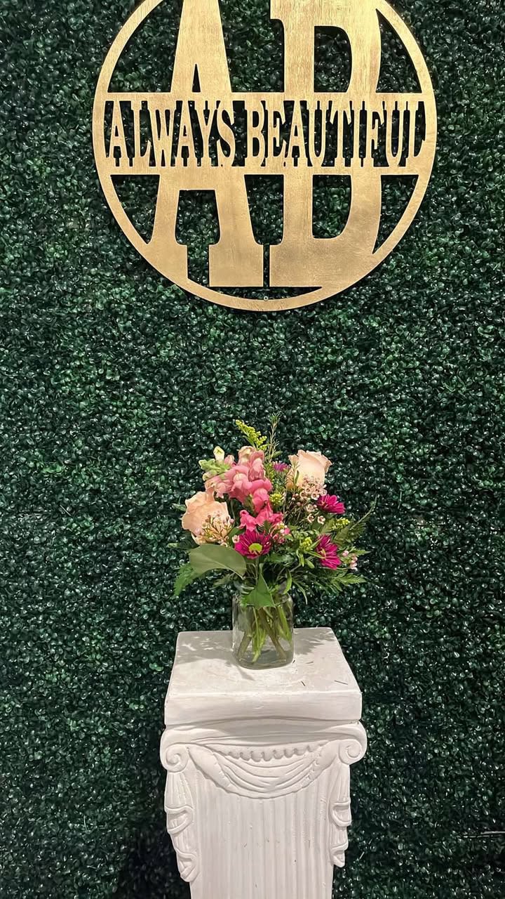 Small mixed flower arrangement in a clear glass vase on a white pedestal