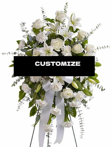 White floral standing spray with lilies and roses on a ribboned easel