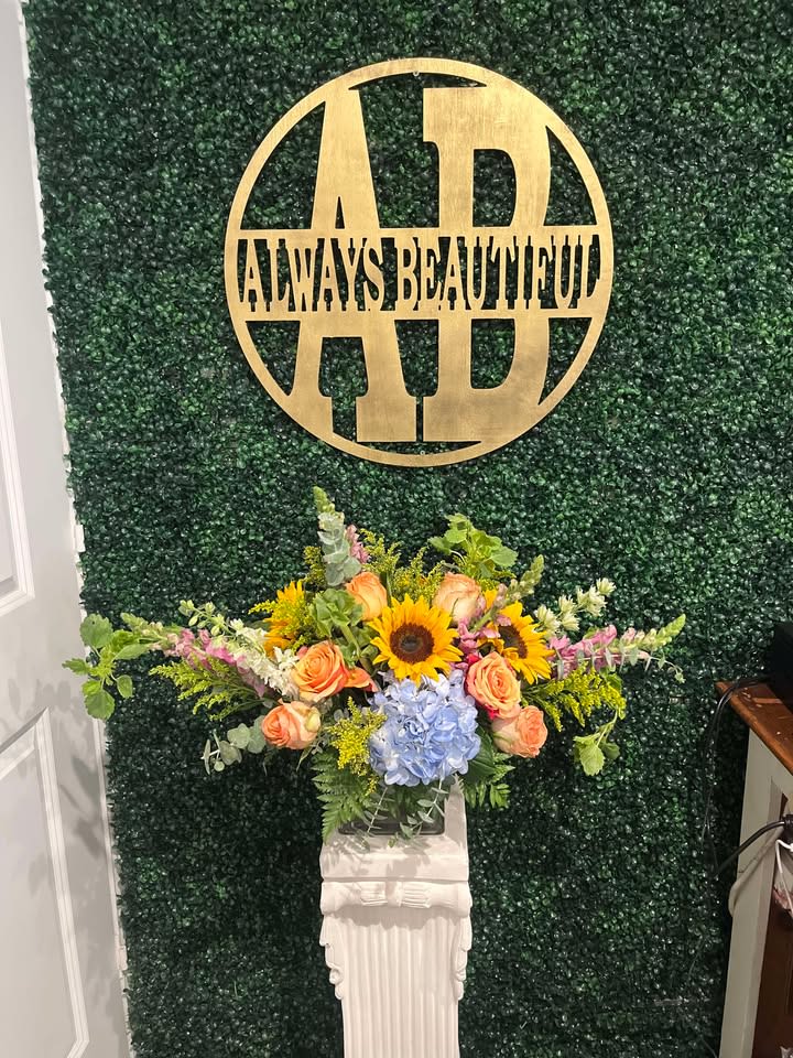Arrangement of sunflowers, peach roses, and blue hydrangea on a pedestal