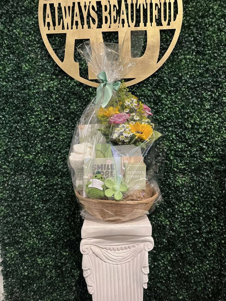 Gift basket with flowers, candles, and a plush toy under clear wrap