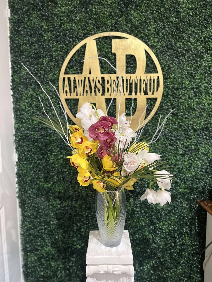 Tall vase arrangement of yellow, white, and purple orchids