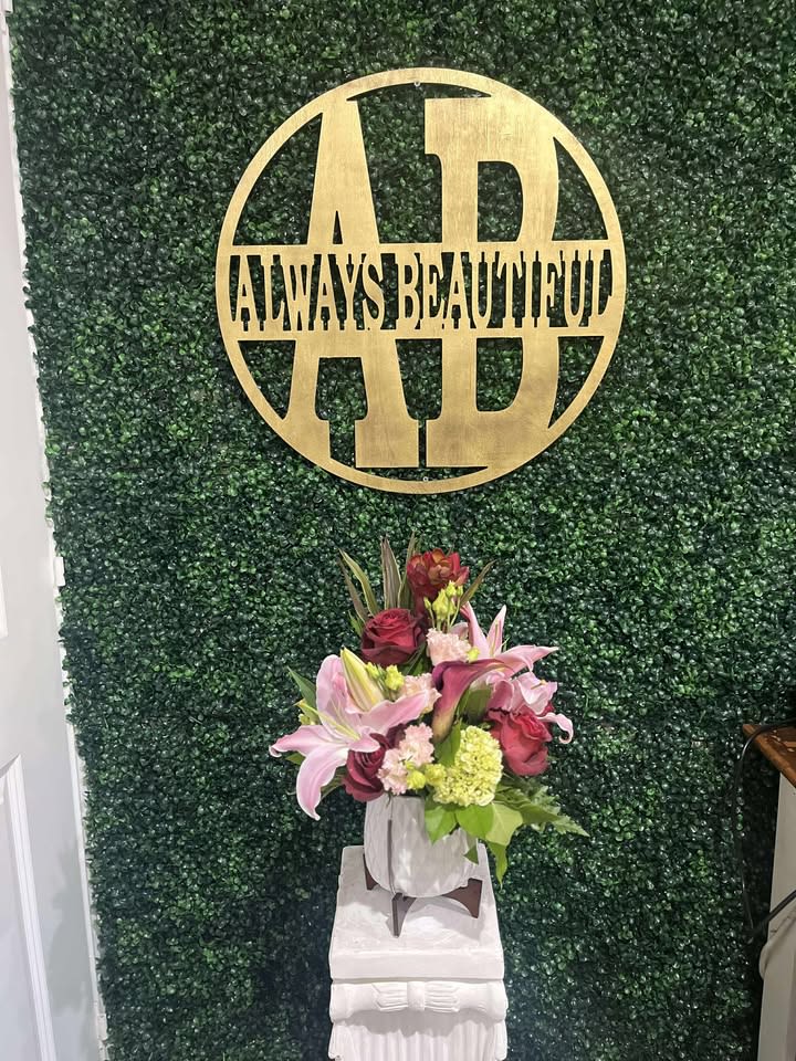 Pink lilies and roses arranged in a white vase on a pedestal