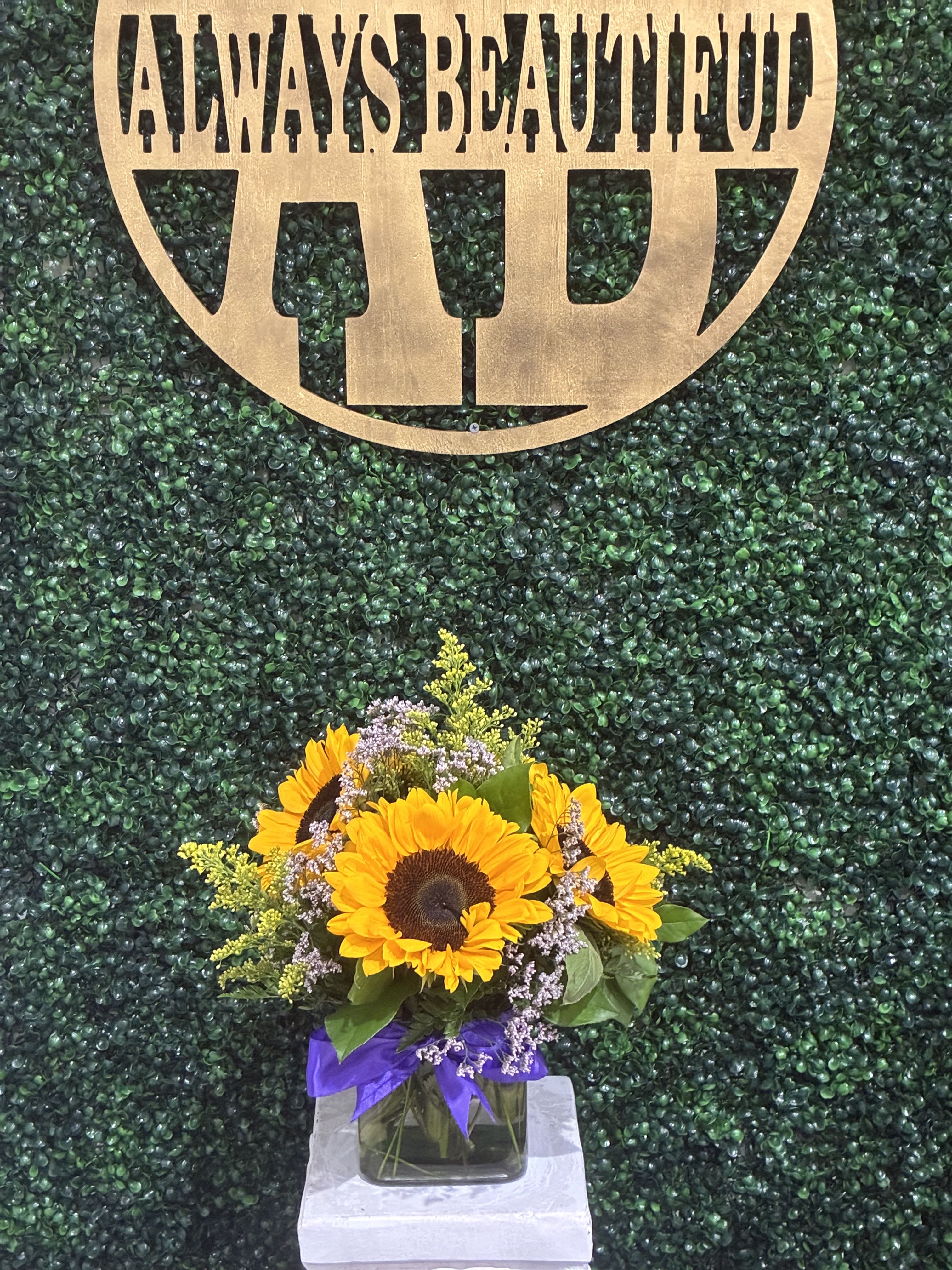 Sunflower bouquet in a glass vase with a purple ribbon