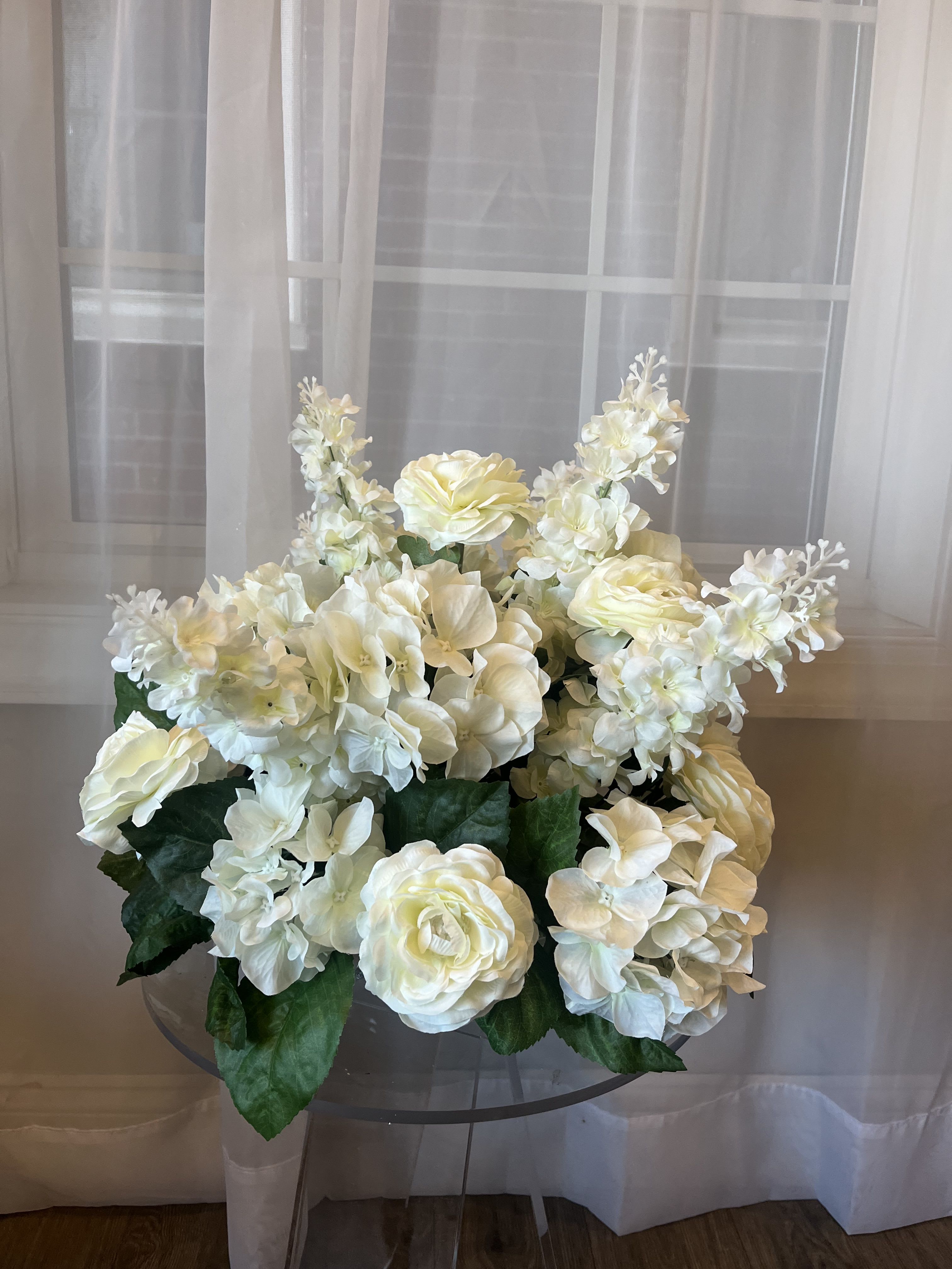White floral arrangement with hydrangeas and roses in a clear vase