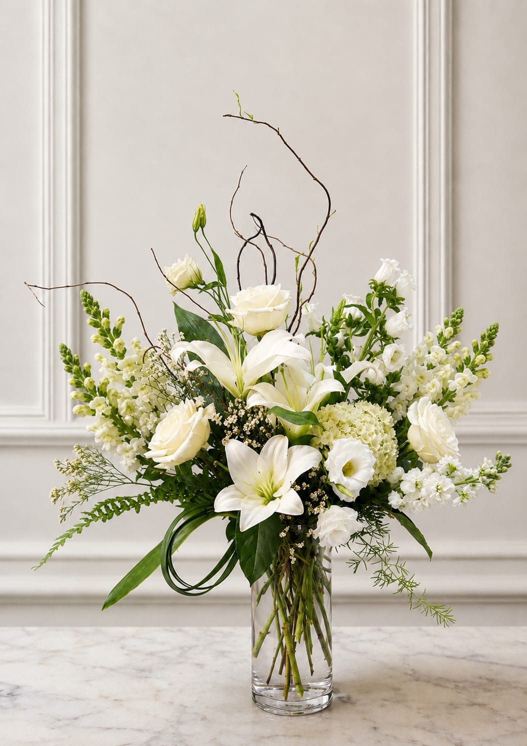 White lilies and roses arranged in a clear glass vase