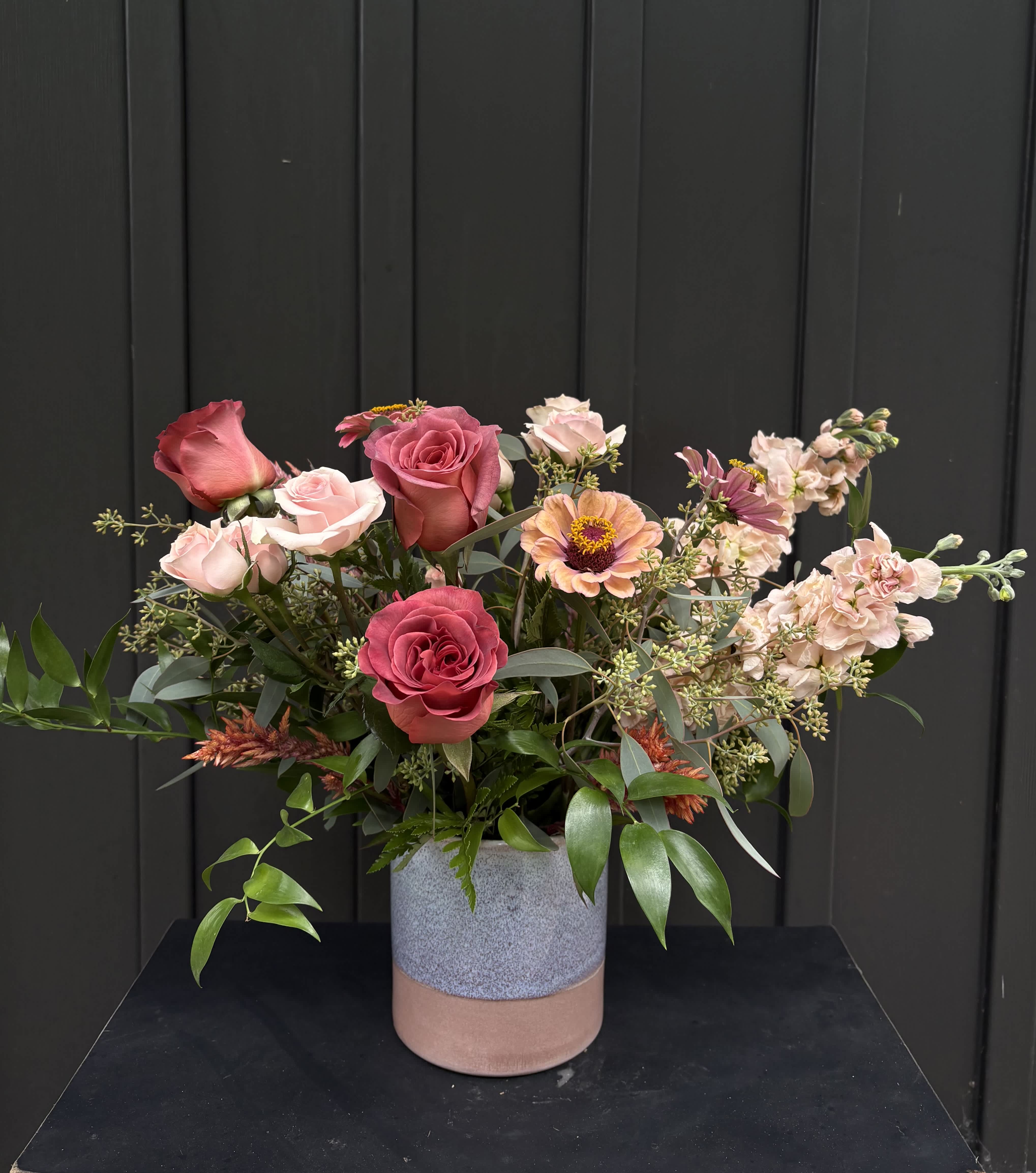 Mixed pink and peach roses in a two-tone ceramic vase