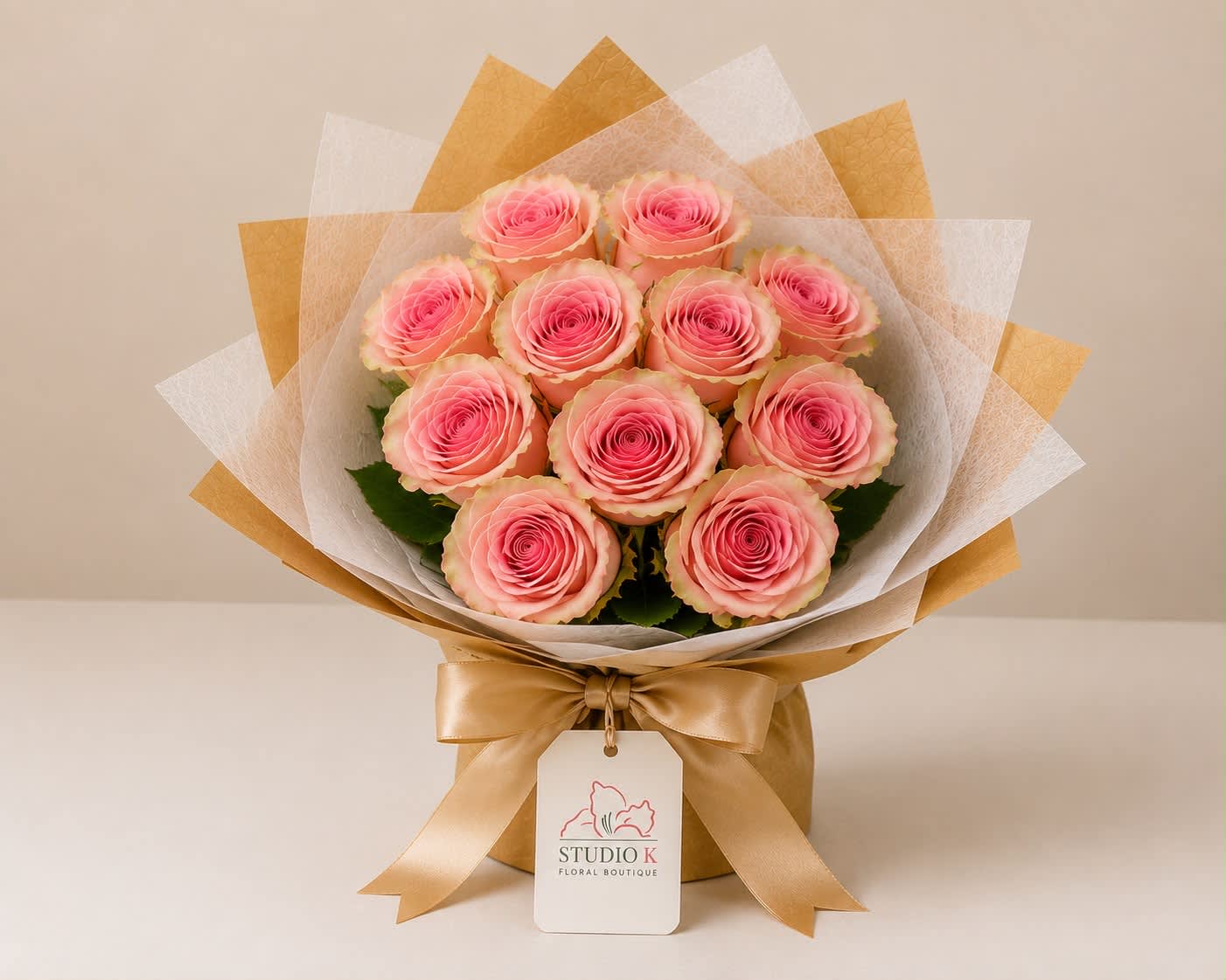 Bouquet of pink roses wrapped in white and gold paper with a satin ribbon