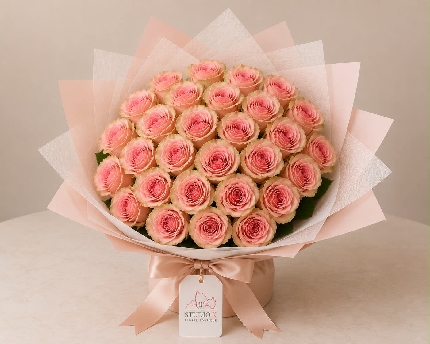 Bouquet of pink roses wrapped in pale pink and white paper with a satin ribbon