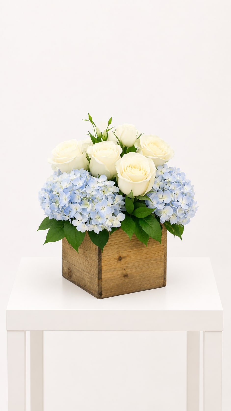 Blue Sky Elegance - Soft blue hydrangeas paired with creamy white roses, thoughtfully designed in a rustic wood cube for a calm, timeless, and elegant look with a natural touch.  Perfect for sympathy, get well wishes, Mother’s Day, thank you gestures, welcoming a new baby, thinking of you, or a meaningful birthday gift.  Available for local flower delivery throughout Naples, Bonita Springs, Estero, Fort Myers and Fort Myers Beach.  Designer’s Choice: Each arrangement is uniquely designed using the freshest seasonal flowers available. Flower varieties, colors and containers may vary while maintaining the overall style, value and beauty of the design.