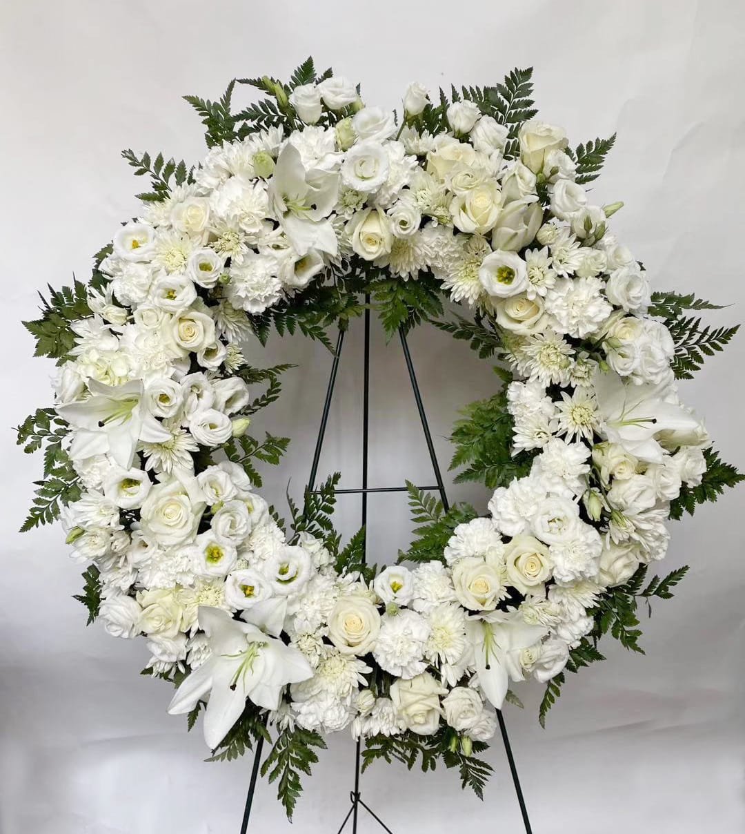 White floral funeral wreath on a black stand