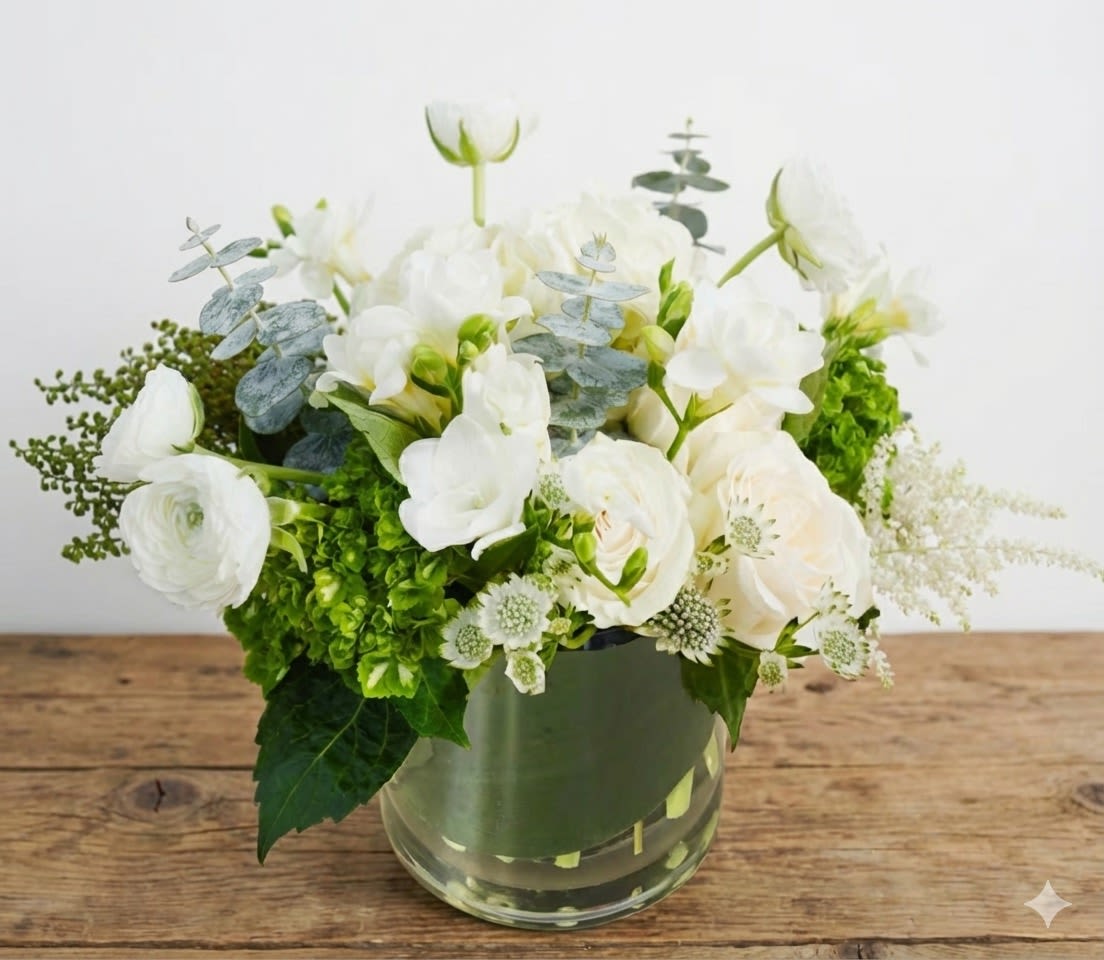 White flowers arranged in a clear glass vase with green accents