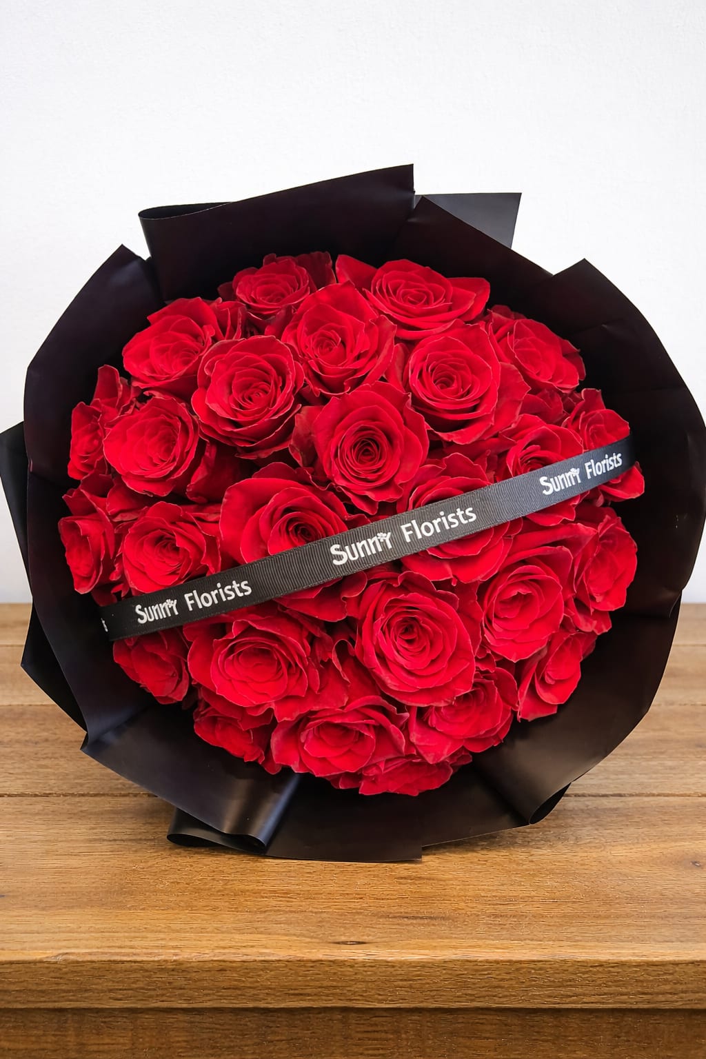 Bouquet of red roses wrapped in black paper with a ribbon