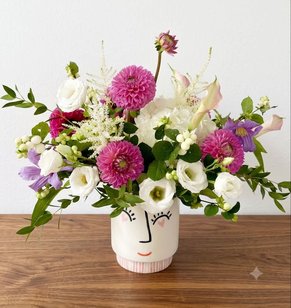 Mixed bouquet in a face-painted ceramic vase with pink, white, and purple blooms