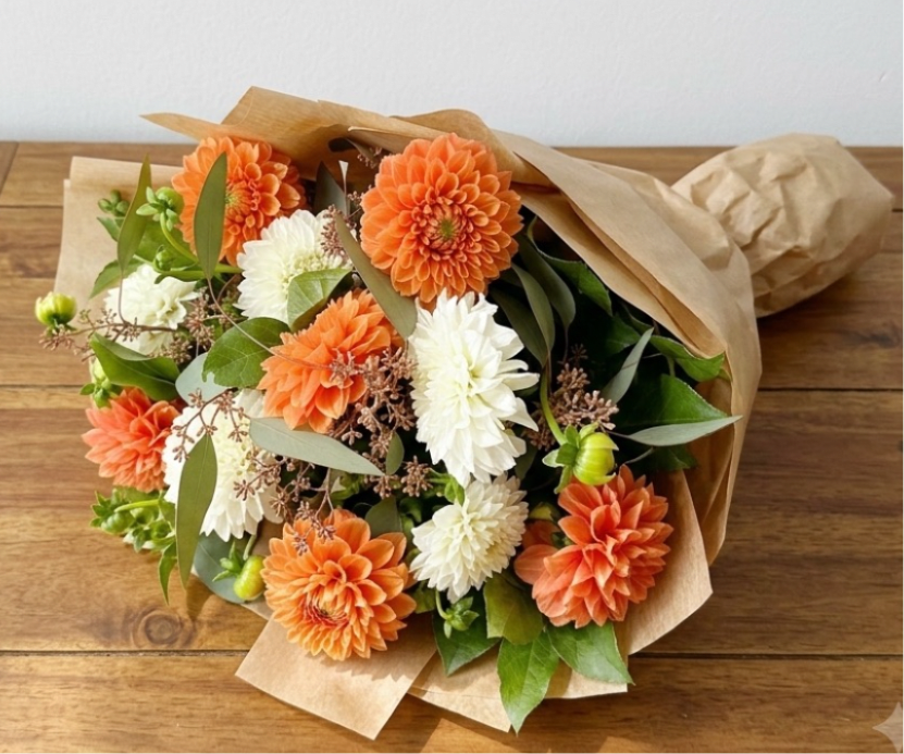 Dozen Dahlias Handtied Bouquet  - This standard size handtied bouquet includes a dozen mixed color dahlias with greenery. A deluxe size includes 2 dozen mixed color dahlias. A premium size includes 3 dozen mixed color dahlias 