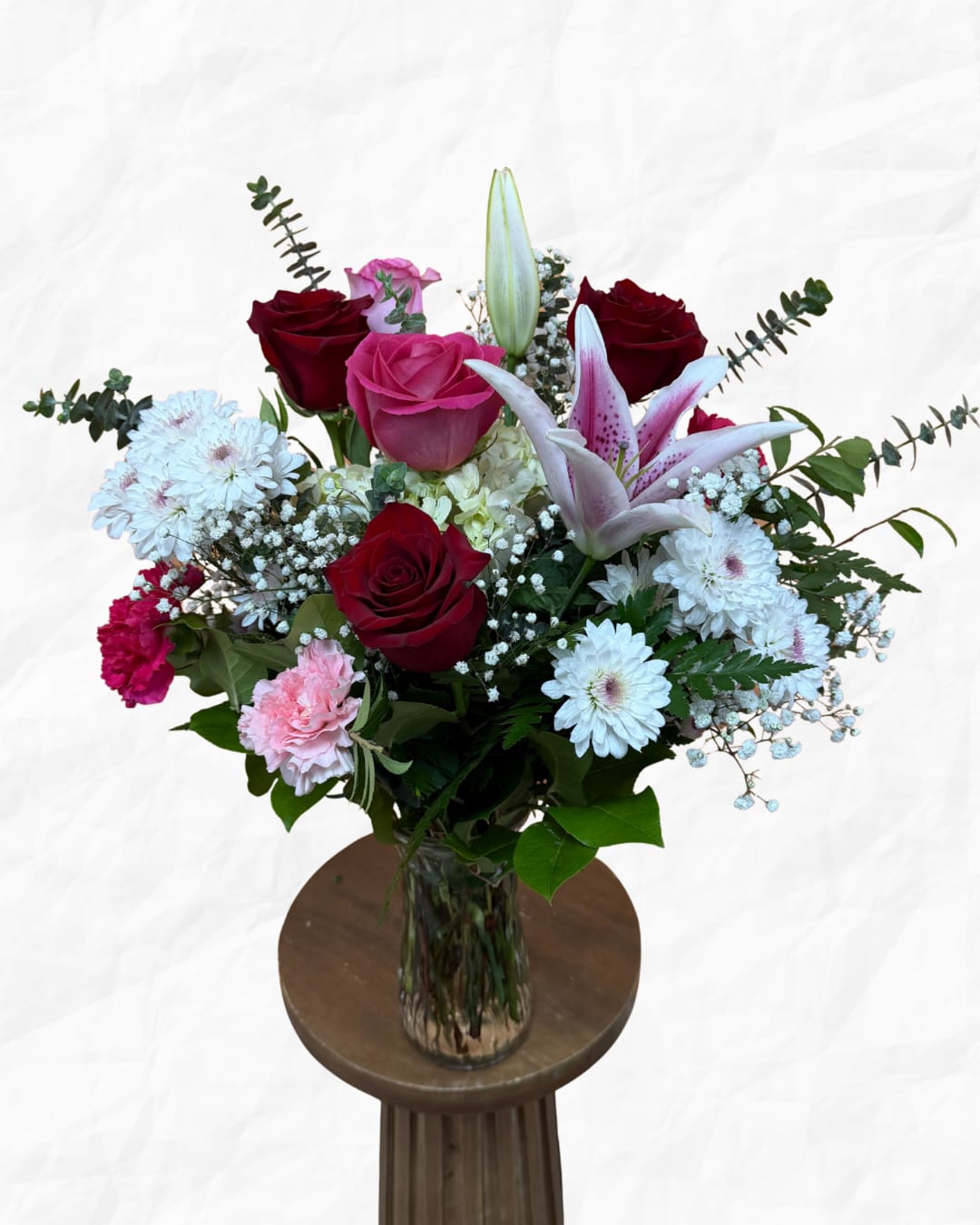 Mixed bouquet of roses, lilies, and daisies in a glass vase
