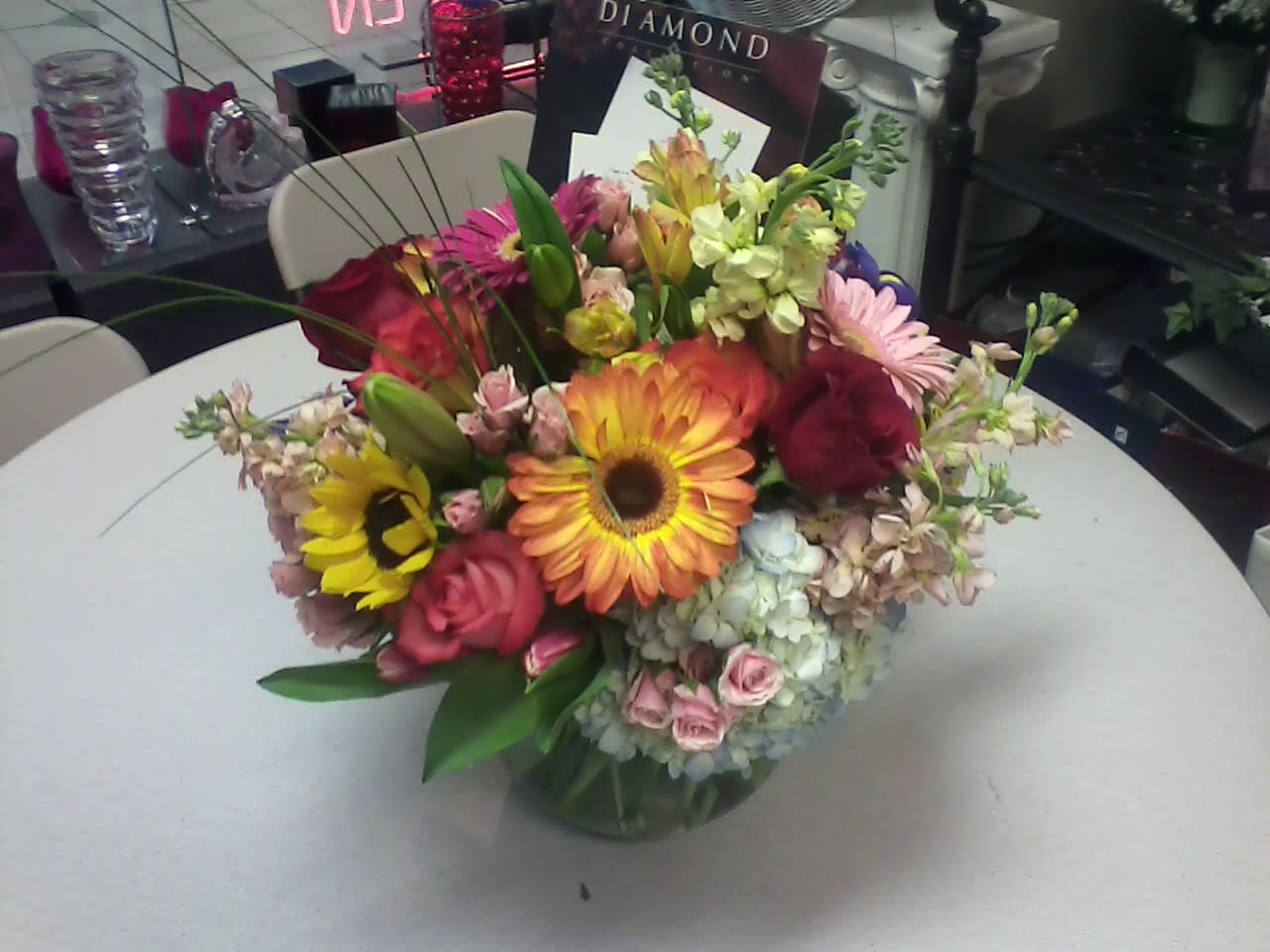 Mixed bouquet with gerbera daisies, roses, and lilies in a glass vase
