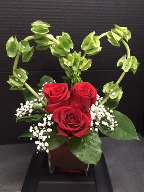 Red roses with baby's breath and green bells of Ireland in a vase