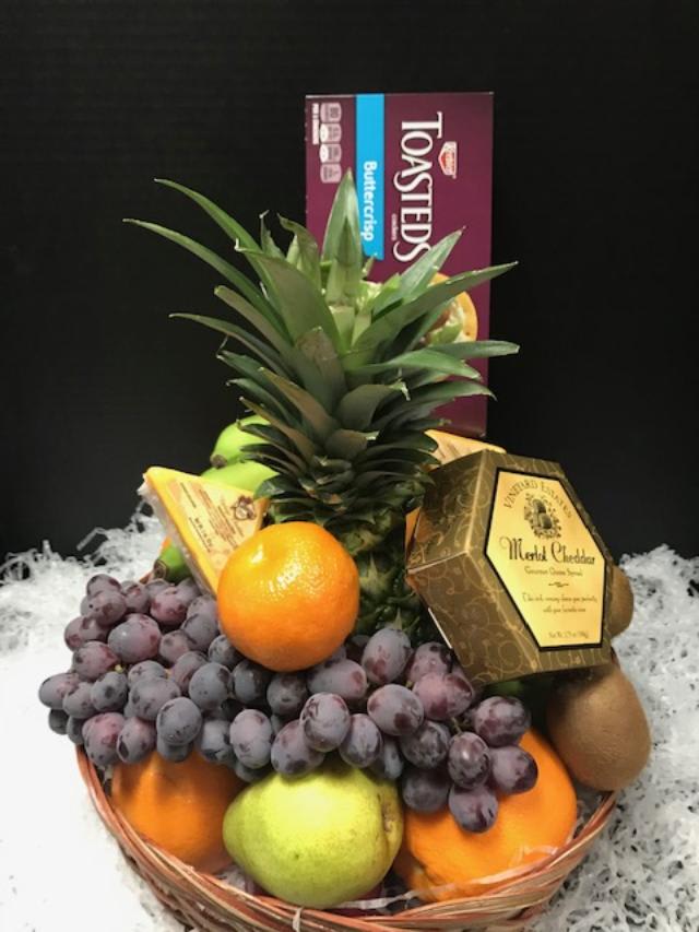 Fruit basket with pineapple, grapes, oranges, pears, and chocolates