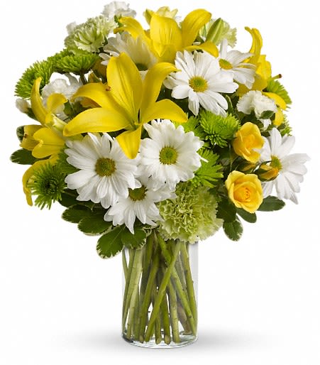 Yellow lilies and white daisies in a clear glass vase
