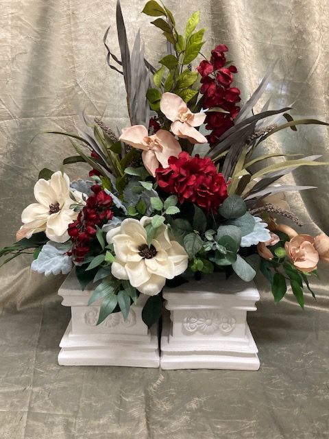 Floral arrangement with cream and burgundy blooms in white pedestal containers