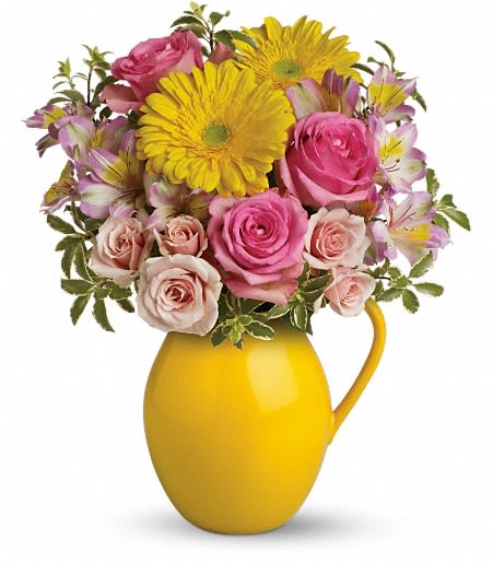 Pink roses and yellow daisies arranged in a yellow pitcher vase