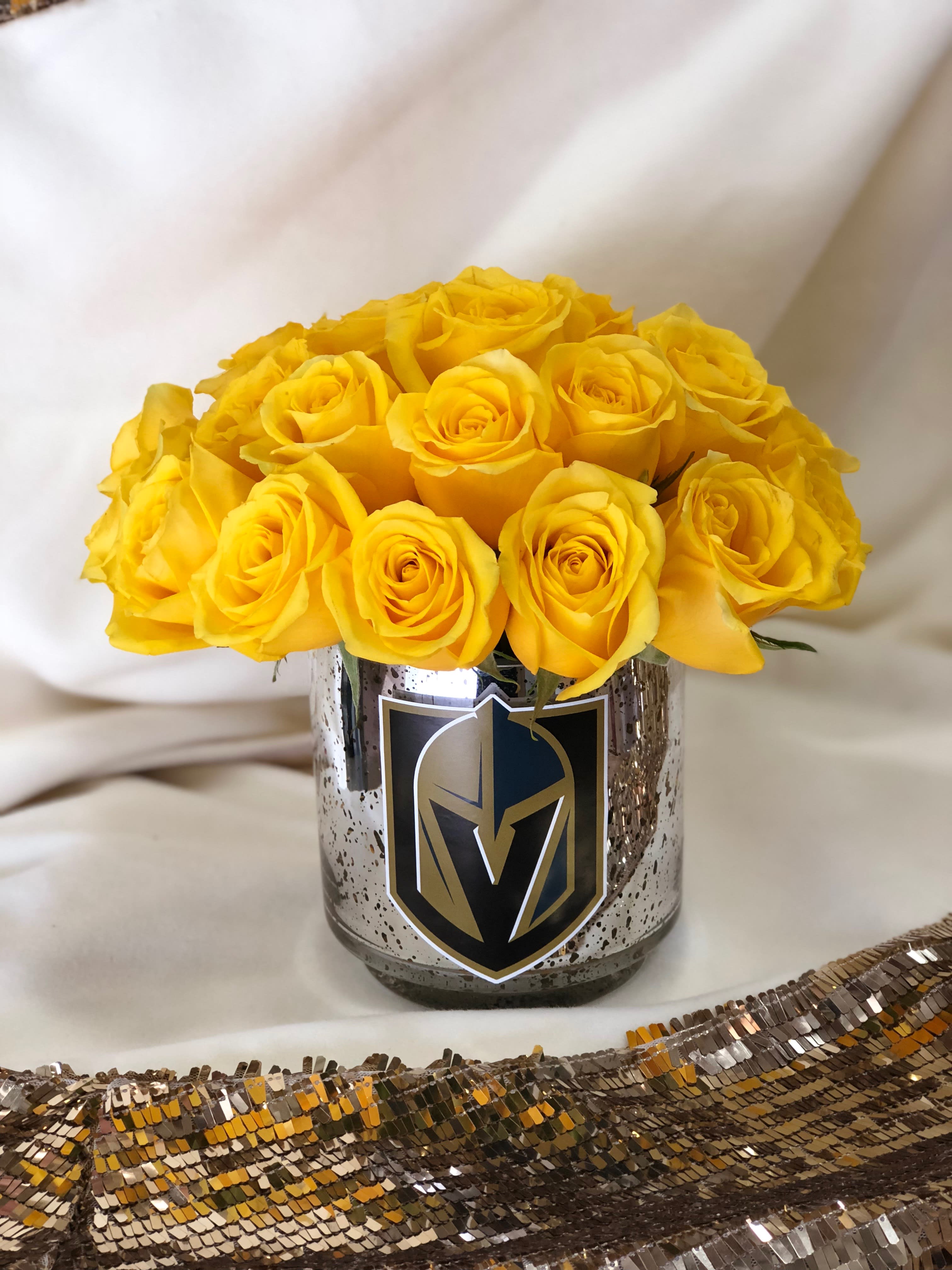 Yellow roses arranged in a metallic vase with a sports logo