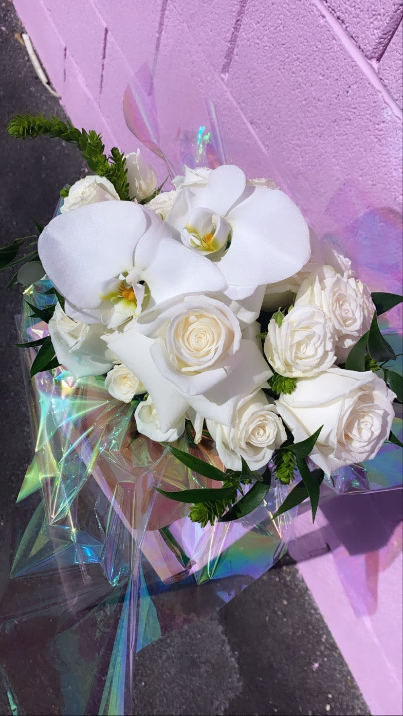 White roses and orchids wrapped in iridescent paper