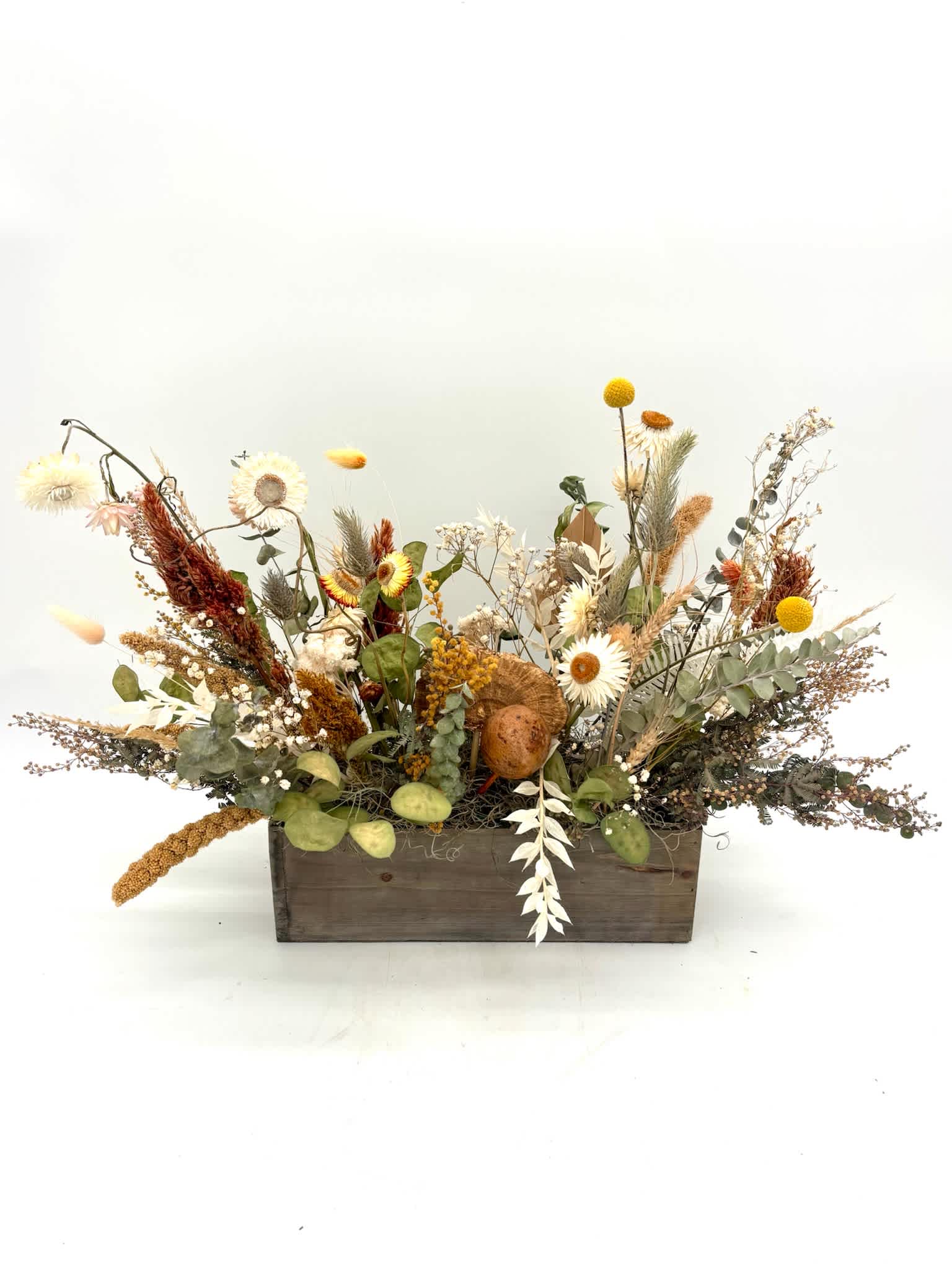 Dried floral arrangement in a wooden box with white and yellow blooms