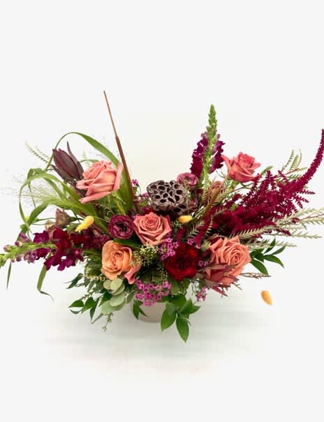 Pink roses and burgundy flowers arranged in a white vase