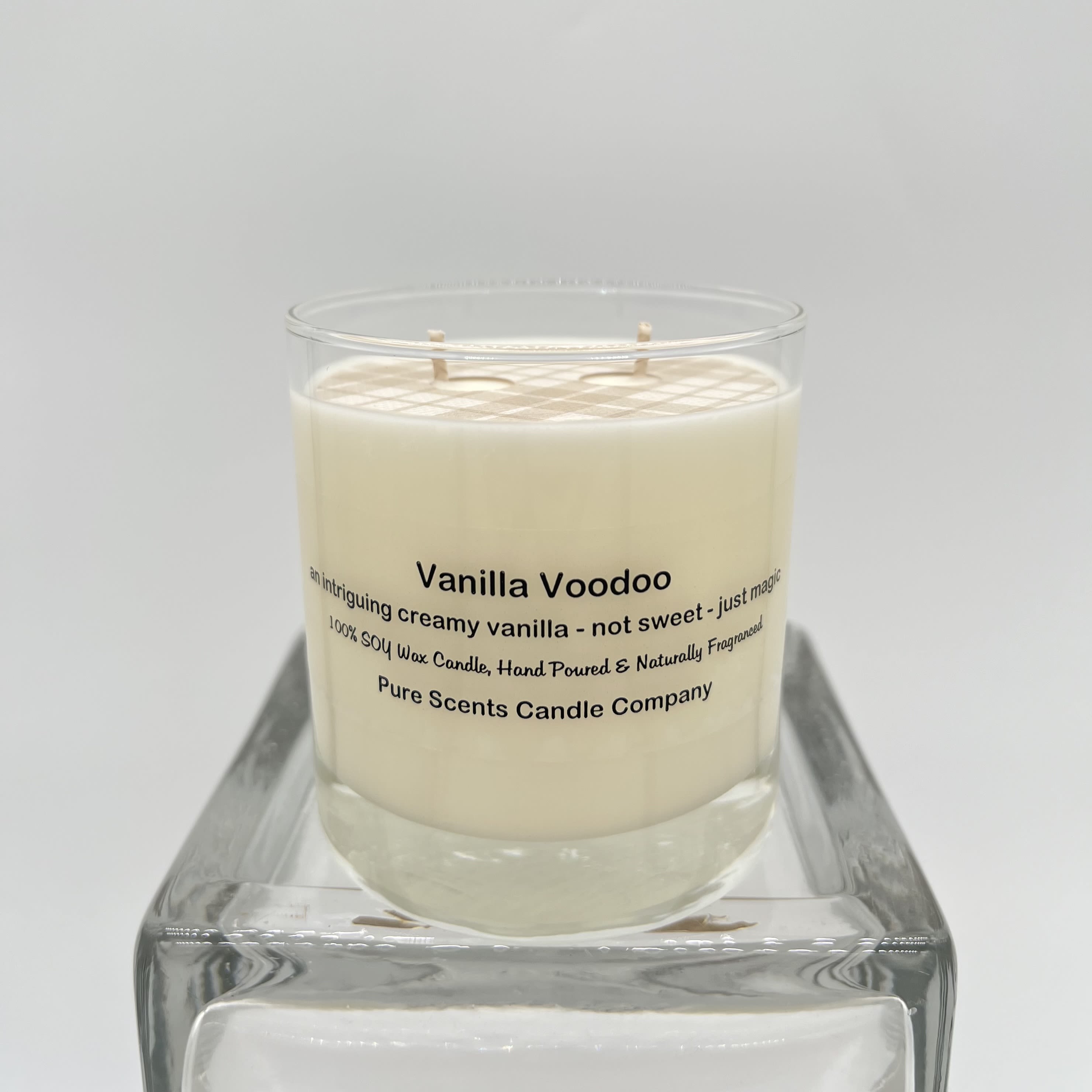Cream-colored vanilla candle in a clear glass jar on a square glass stand