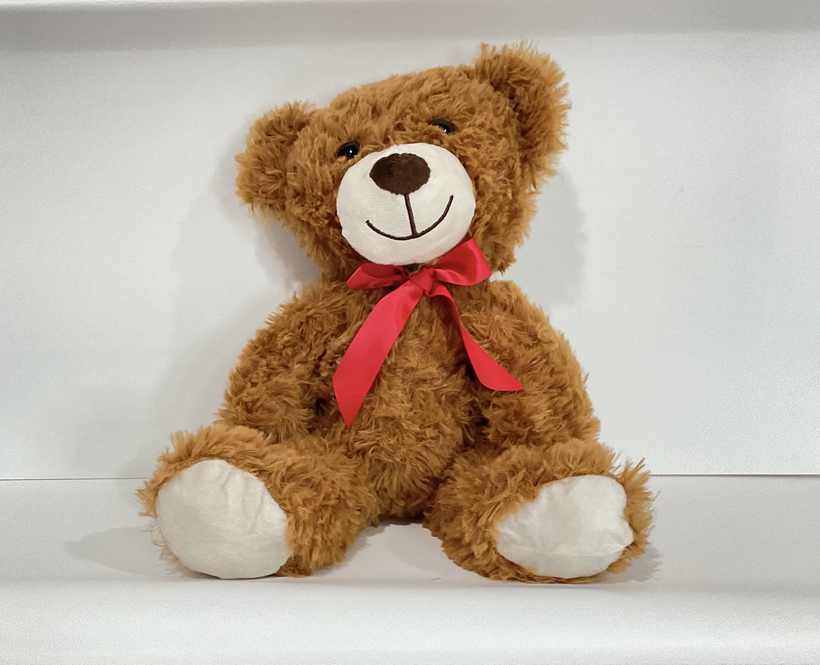 Brown teddy bear with a red ribbon bow