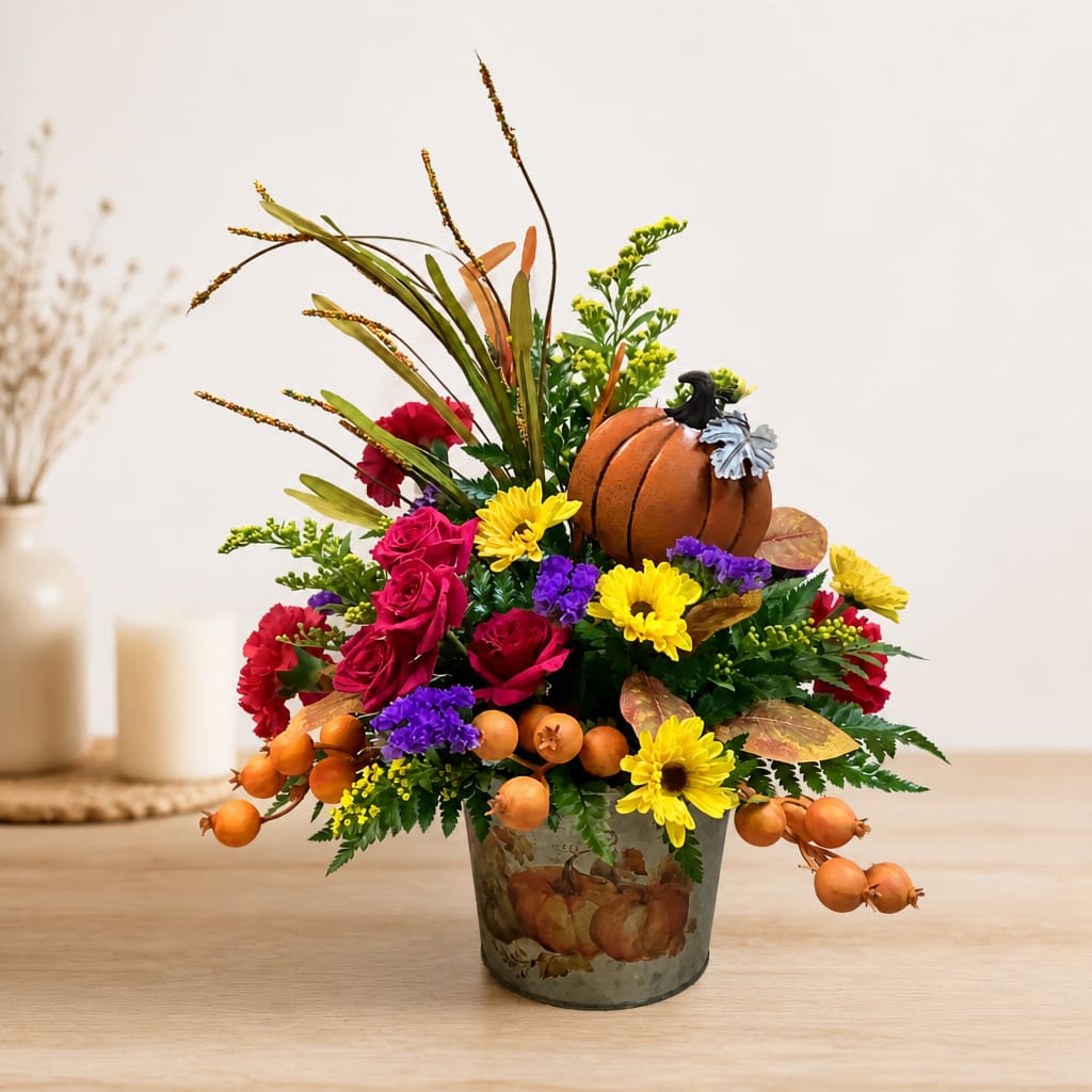 Fall floral arrangement in a pumpkin-decorated metal pot with a small pumpkin accent