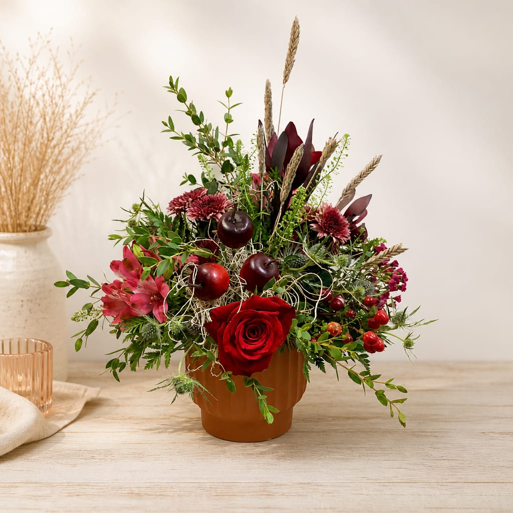 Red rose arrangement in a brown pot with berries and wheat stems
