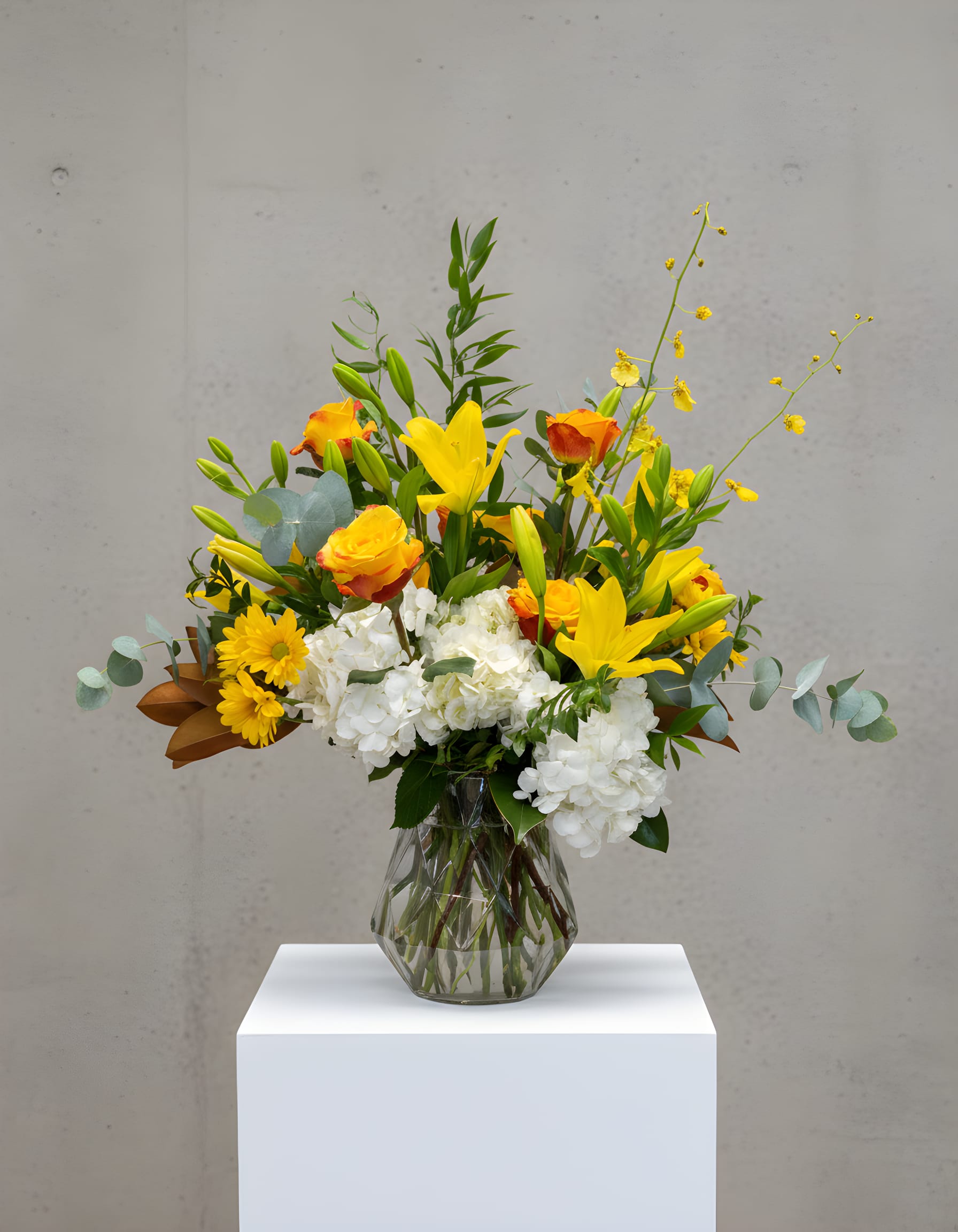 Yellow lilies and roses with white hydrangeas in a glass vase
