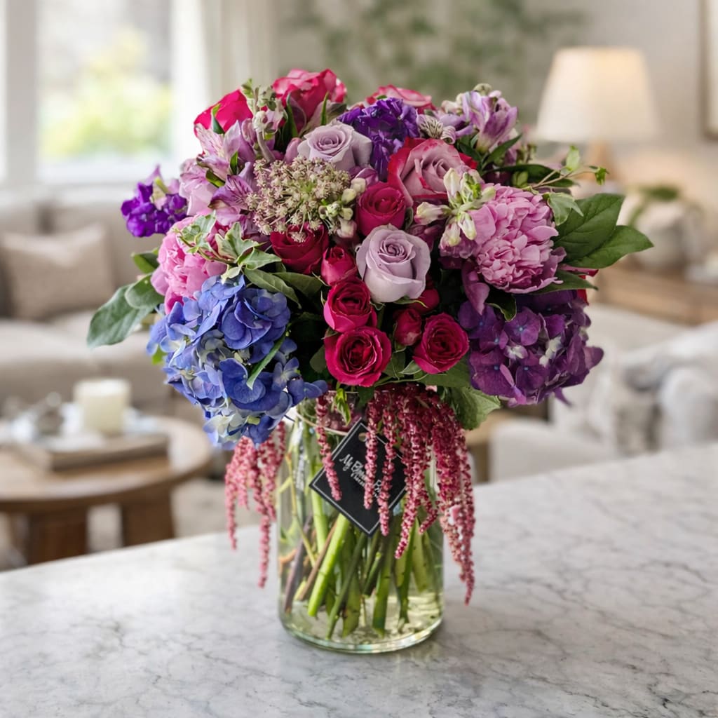 Radiance - Add some luxury to your living space with the stunning Radiance arrangement. This one-of-a-kind display piece will bring a sense of warmth, peacefulness, and beauty to any room. It features a gorgeous combination of lush jewel-tone flowers like Hydrangeas, Roses, Lisianthus, and Spray Roses that create a breathtaking bouquet perfect for any occasion. With a stunning clear glass vase and hanging Amaranthus, your family and friends will be reminded of the beauty of nature every time they enter the room.