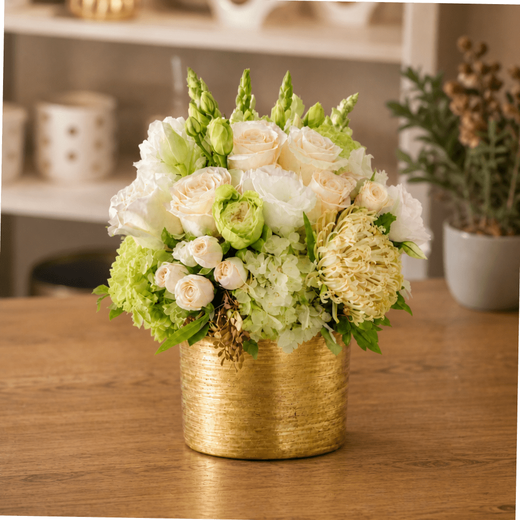 White and pale green floral arrangement in a gold container