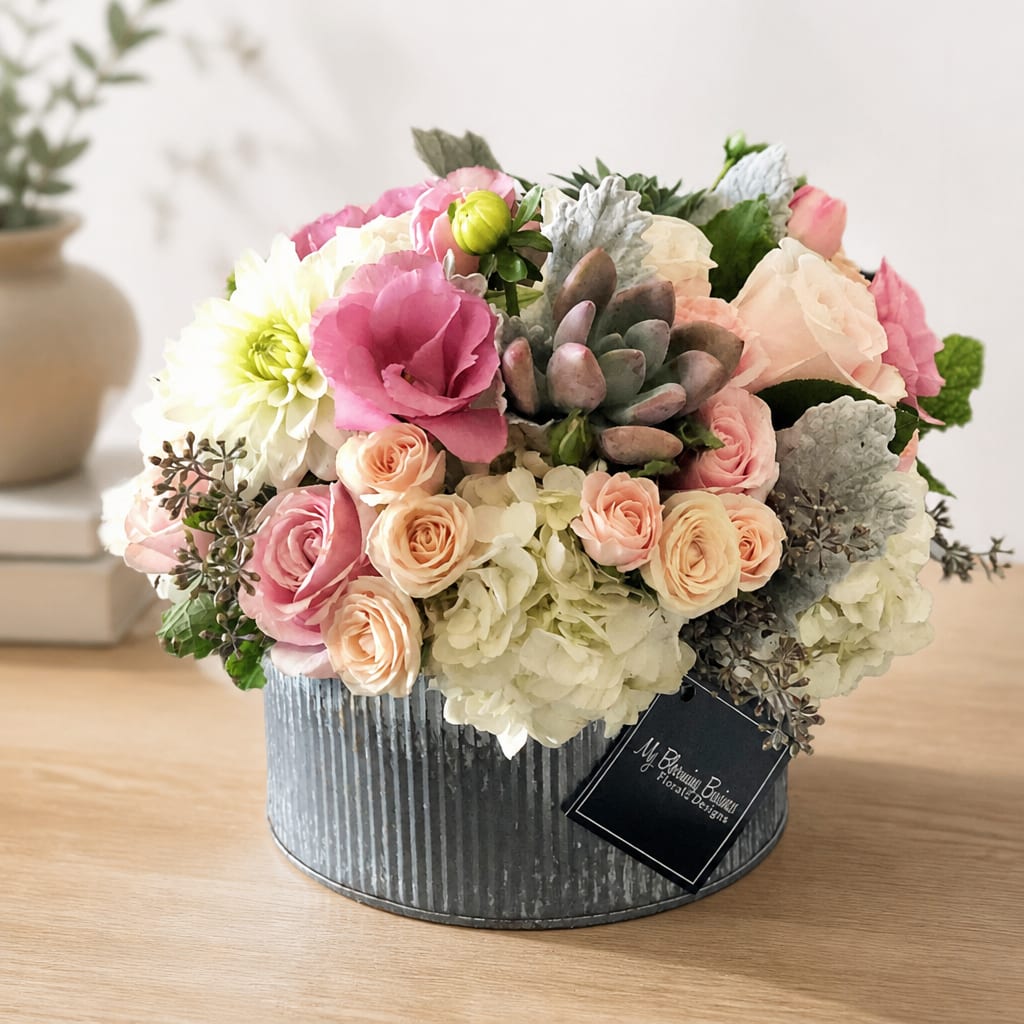 Pink and cream flower arrangement in a ribbed metal box