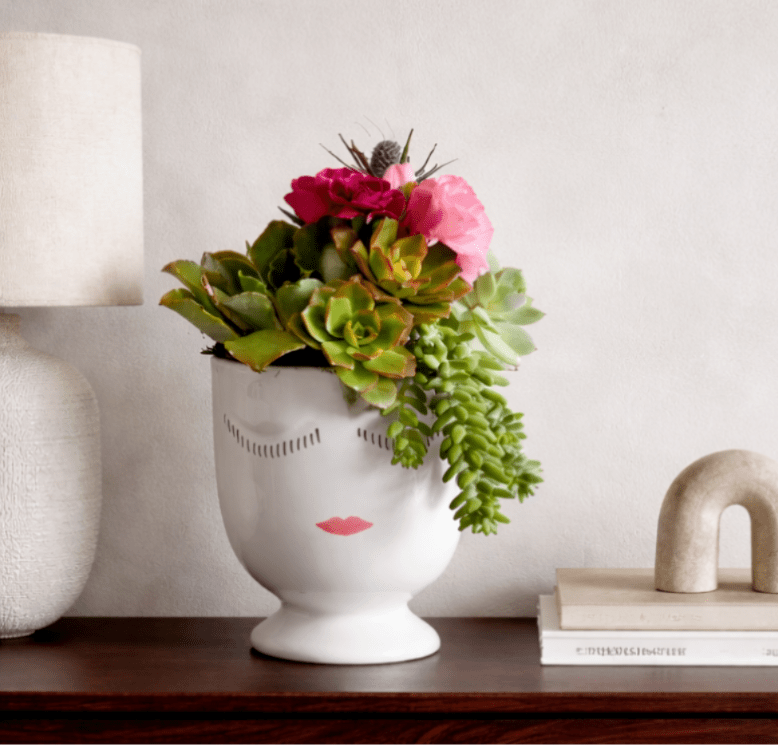 Succulent arrangement in a white face vase with pink flowers