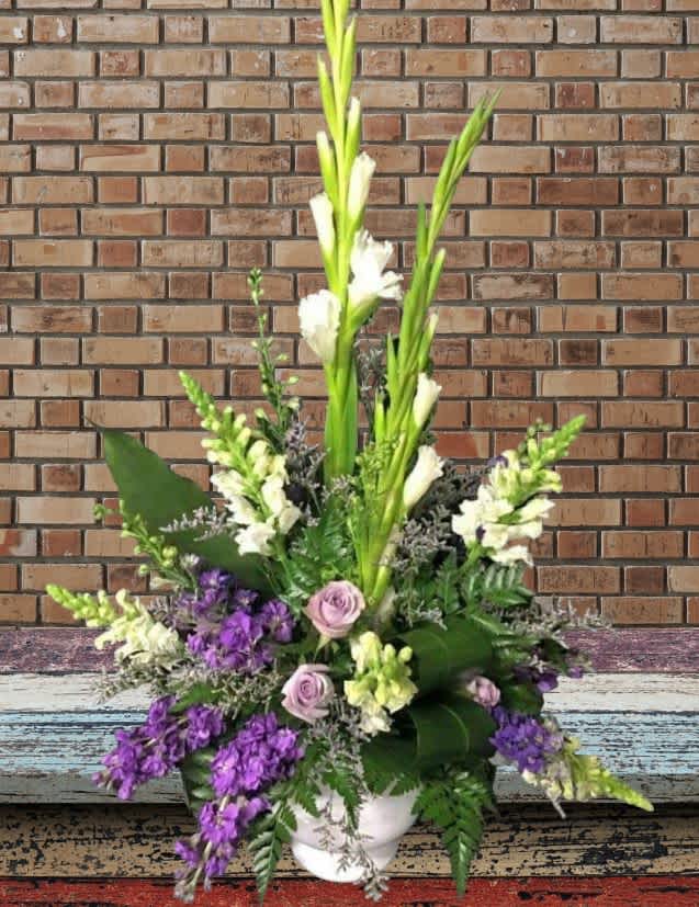 Tall floral arrangement with purple and white blooms in a white vase